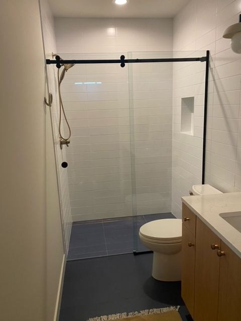 Barn door slider with a black header in a narrow bathroom