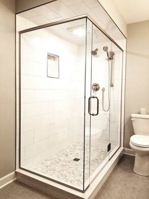 Frameless corner shower with black hardware and marble tile