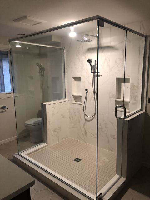 Frameless corner enclosure with a dark tile floor