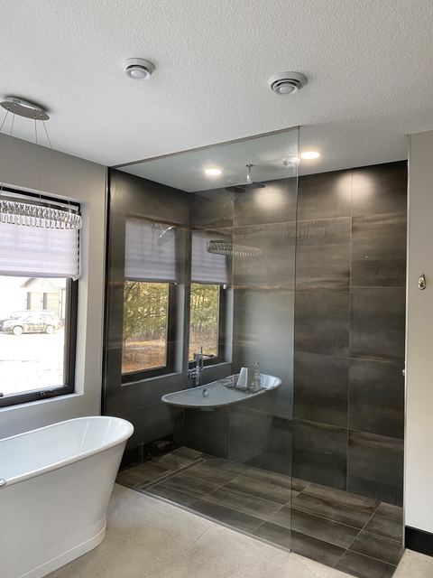 Frameless glass wall in a wet room with a freestanding tub