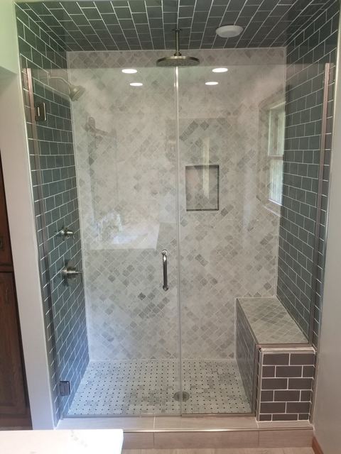 Frameless steam shower with green tile and a bench