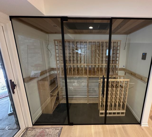 Black-framed glass wall and door into a basement wine room