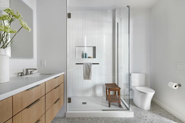 Frameless corner shower next to a vanity and mirror