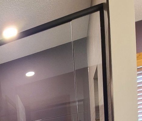 Back-painted shower wall seen through the glass, with the matching painted wall of the next room at the right edge