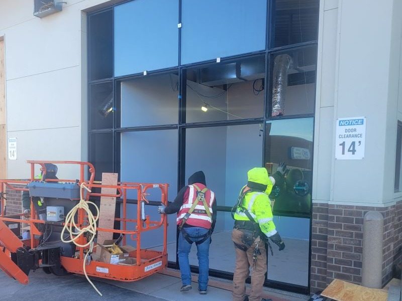 Glaziers setting a storefront lite on a commercial job site