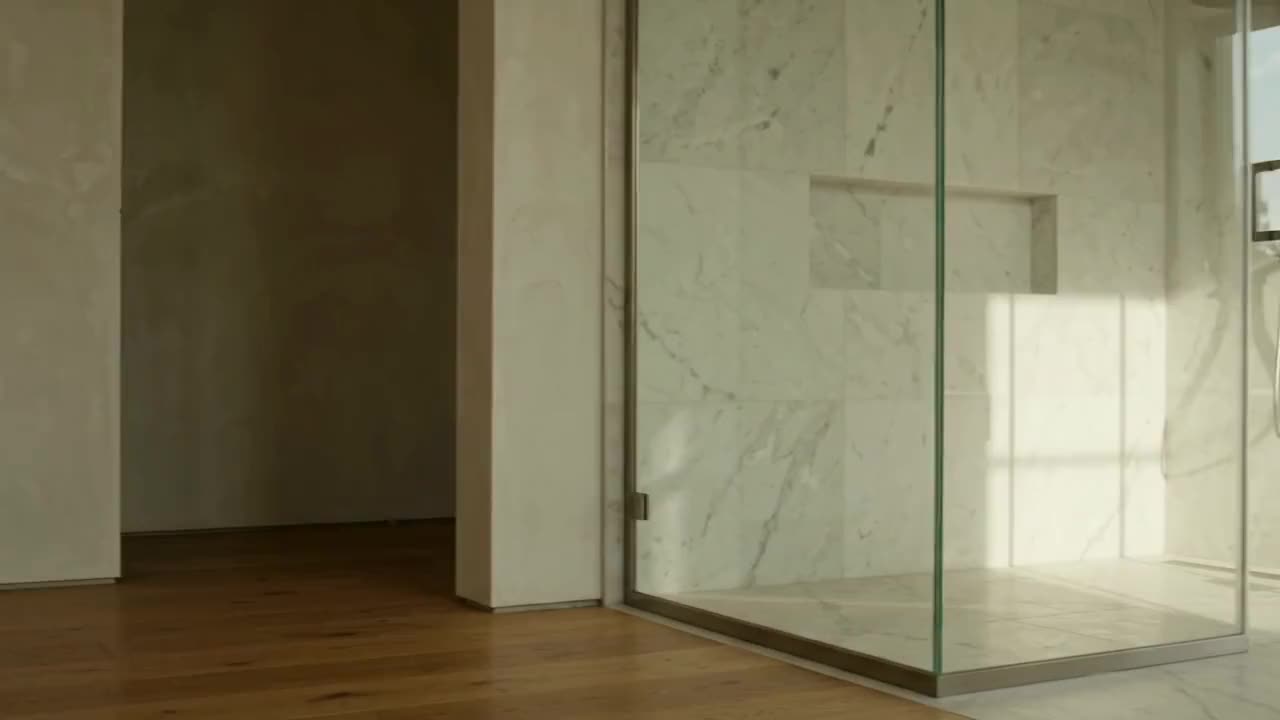 Frameless glass enclosure in a sunlit marble room